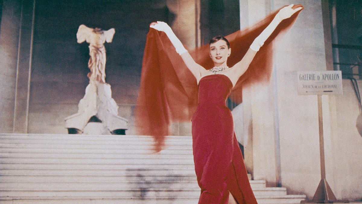 Audrey Hepburn descending down a flight of stairs in a red dress