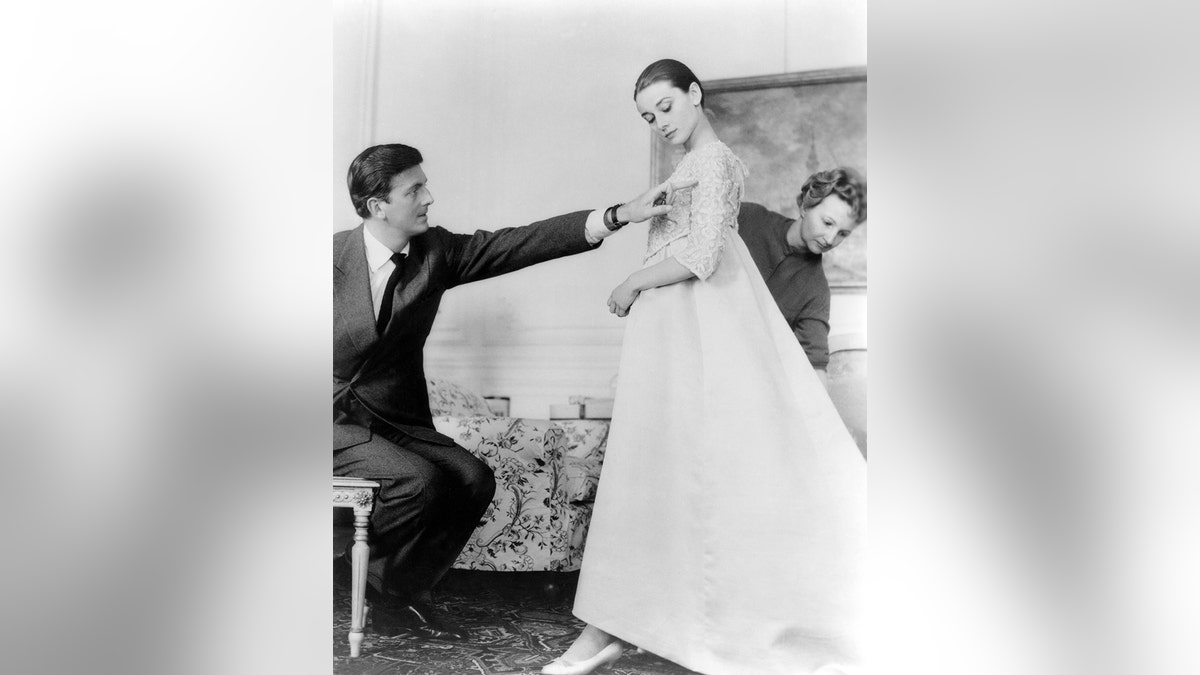 Hubert Givenchy hemming a dress on Audrey Hepburn