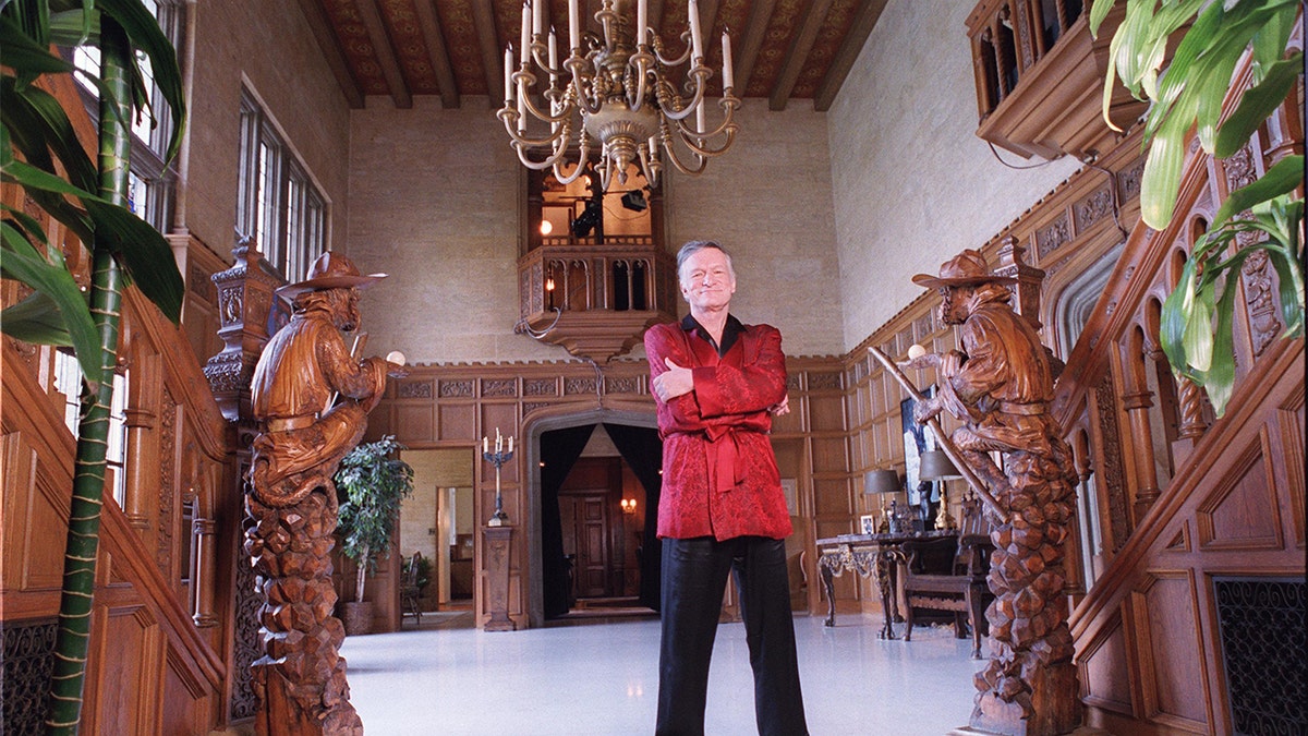 Hugh Hefner wearing a red robe inside his mansion