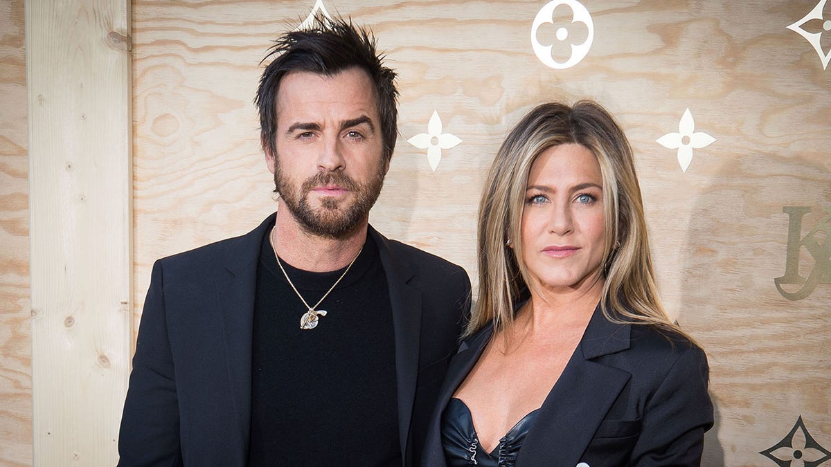Justin Theroux and Jennifer Aniston wearing matching black outfits looking serious
