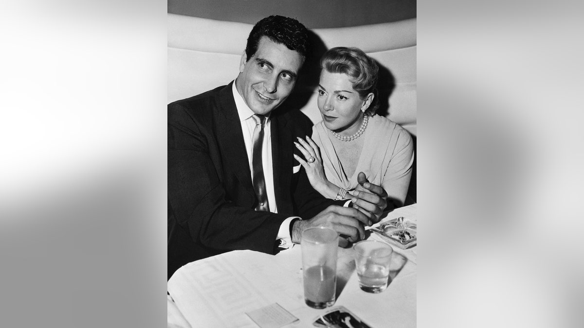 Johnny Stompanato smiling next to Lana Turner at a dinner table