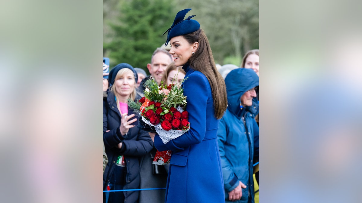 Kate Middleton wearing a blue coat dress holding a bouquet of roses