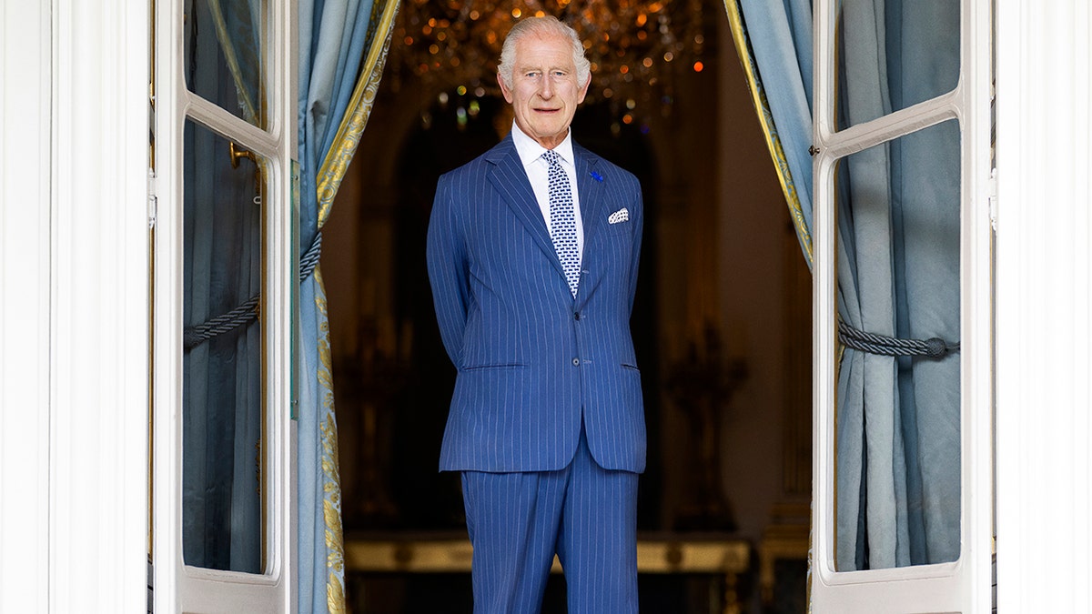 Rei Charles vestindo um terno azul em pé e parecendo sério