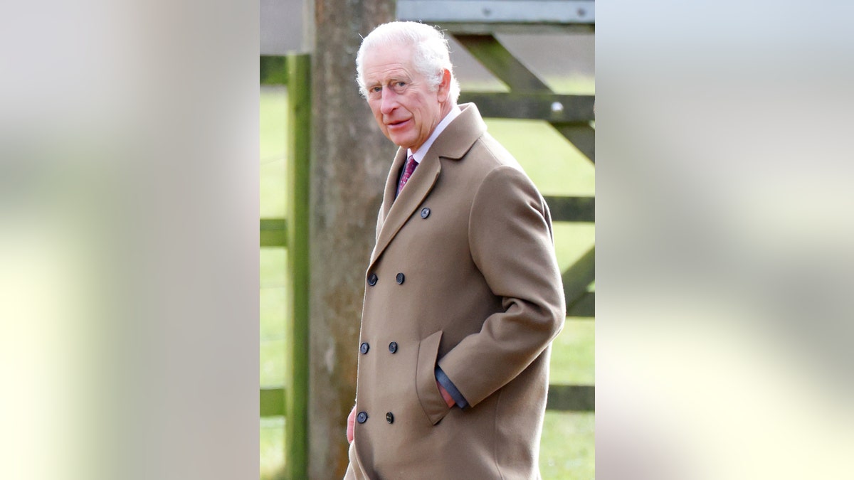 Koning Charles draagt ​​een lichtbruine jas met zijn handen in zijn zakken
