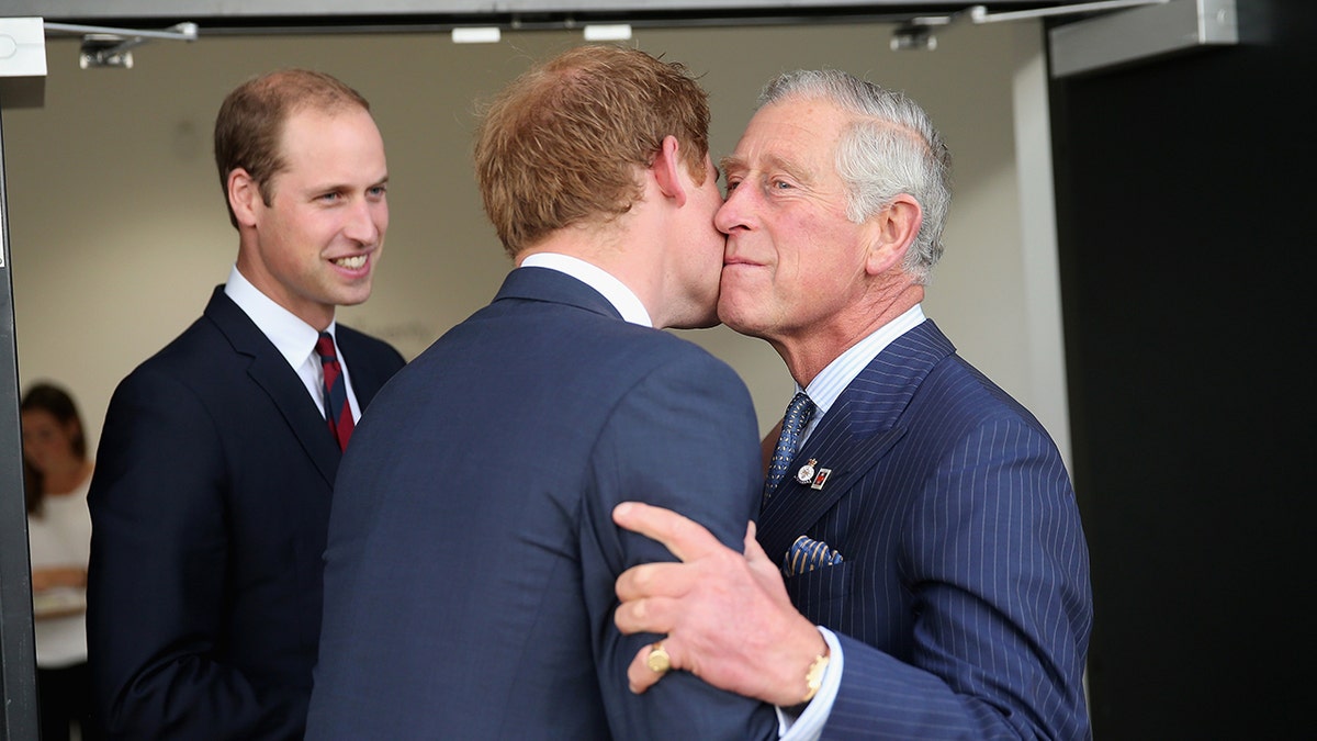 King Charles kissing Prince Harry on the cheek as Pirince William