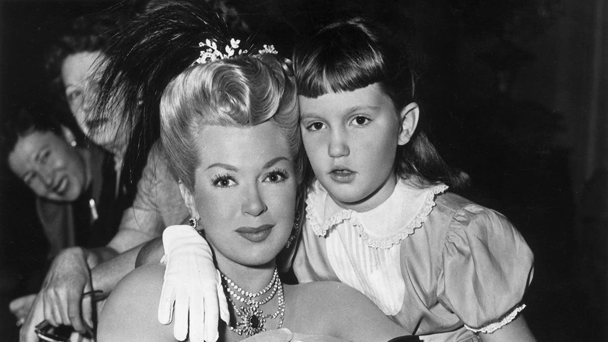 Lana Turner being held by her daughter Cheryl Crane