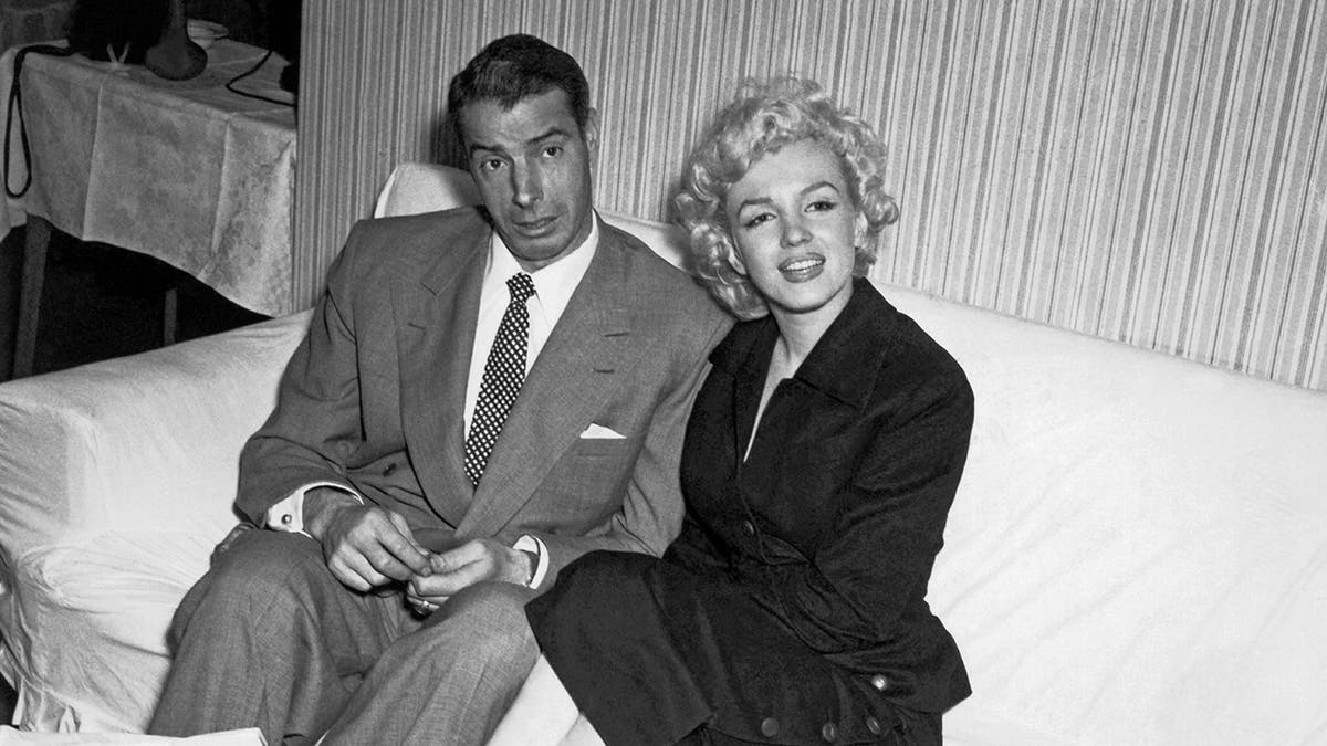 Marilyn Monroe and Joe DiMaggio sitting next to each other
