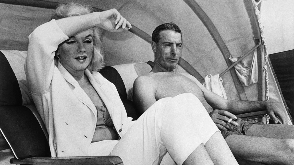 Marilyn Monroe and Joe DiMaggio sitting together by the beach