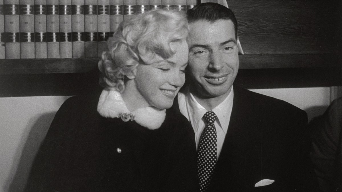 Marilyn Monroe leaning on Joe DiMaggio on their wedding day