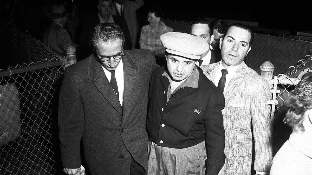 Mickey Cohen being escorted by a group of men