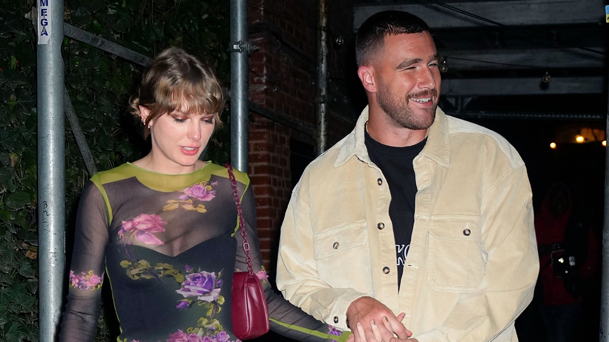 Taylor Swift in a floral outfit walking alongside her boyfriend Travis Kelce
