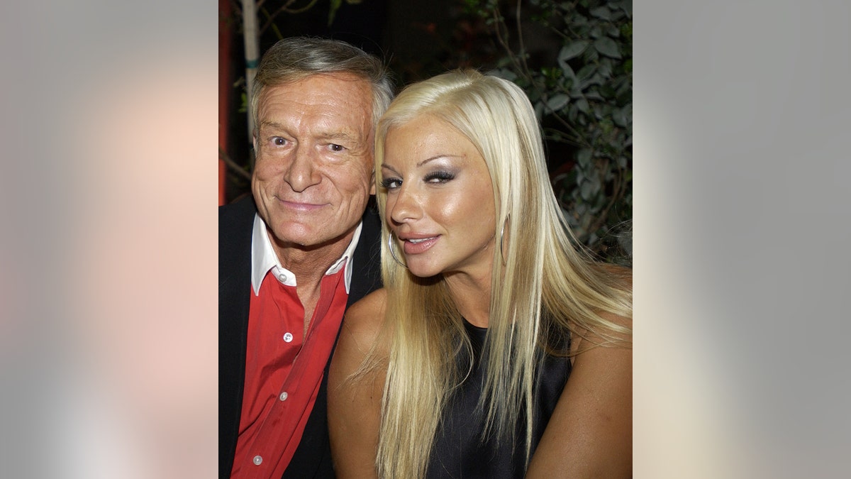 Zoë Gregory smiling next to Hugh Hefner as they lean against each other