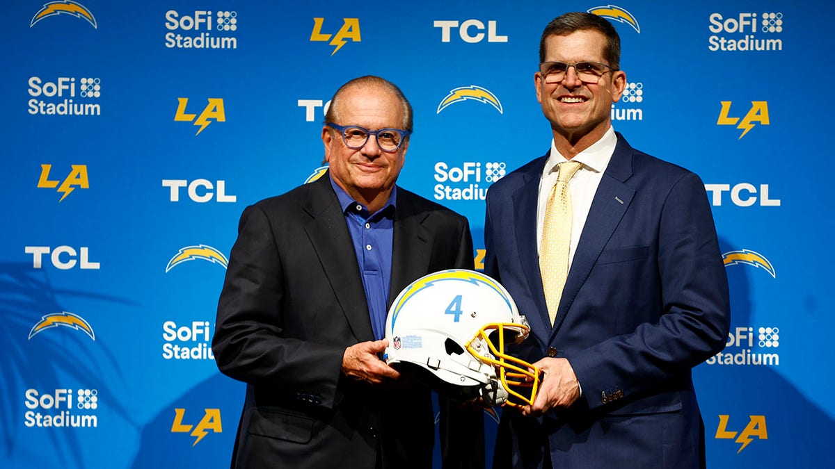 Jim Harbaugh stands with Chargers owner Dean Spanos