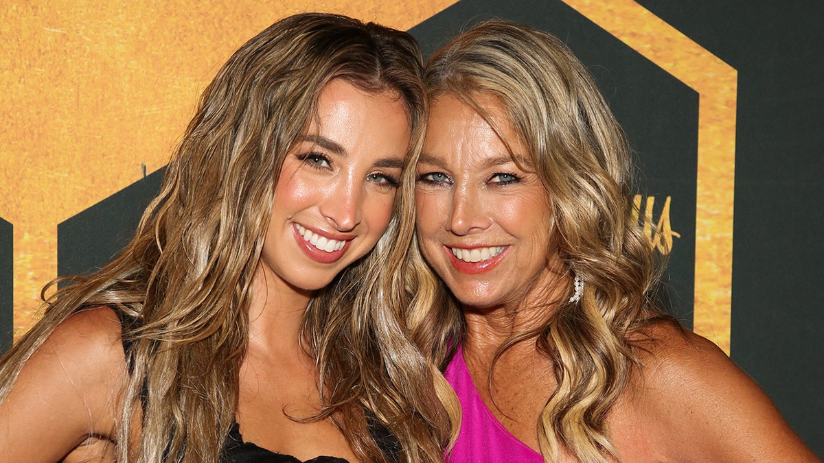 Katie Austin and Denise Austin leaning in together on the red carpet
