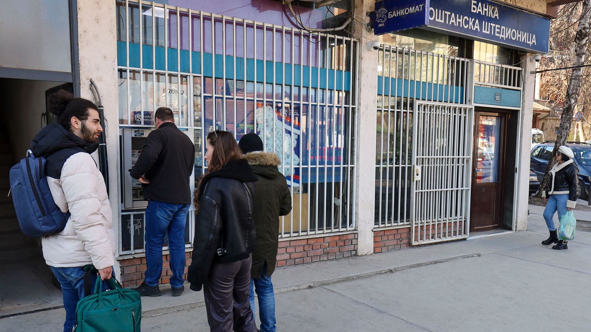 People line up at a cash machine in northern Serb-dominated part of ethnically divided town of Mitrovica, Kosovo