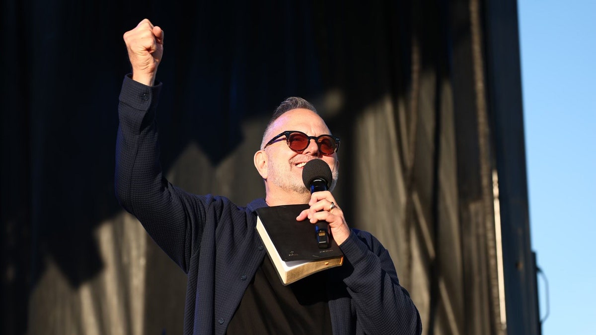 Marcos Witt holding a book and microphone