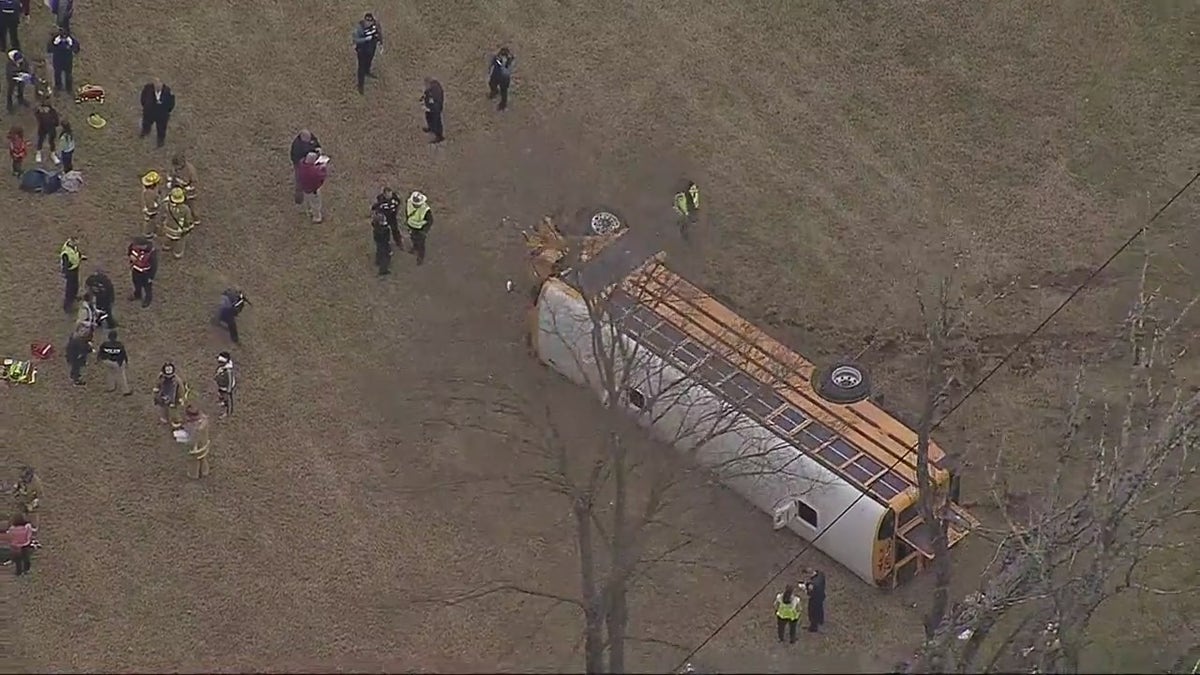 People standing around the bus that is on its side