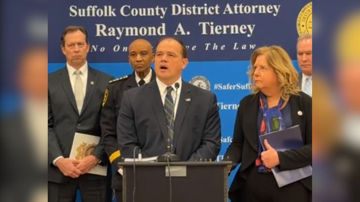 District Attorney Ray Tierney speaking at a press conference flanked by law enforcement,