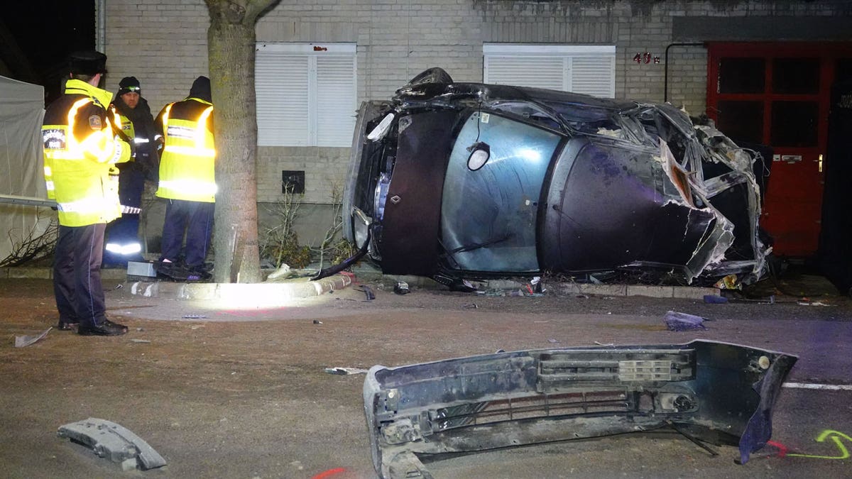 Police investigators stand next to a crashed car in Serbia