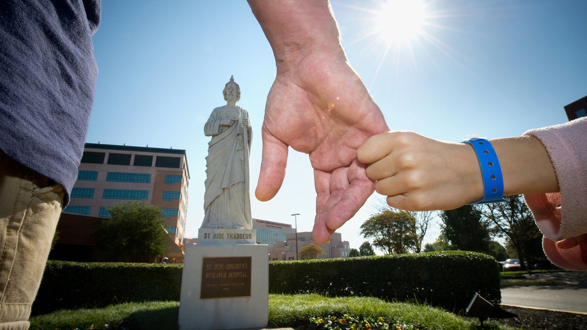 People holding hands in front of St. Jude's statue