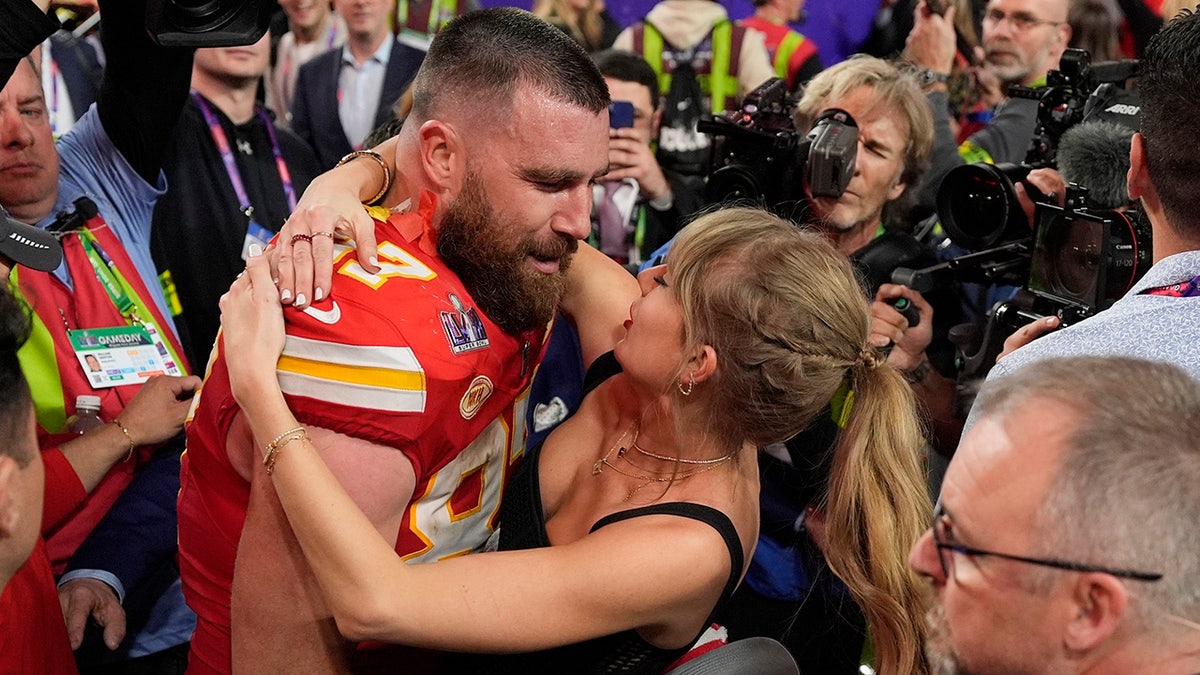 Taylor Swift olha carinhosamente para Travis Kelce em seu uniforme vermelho do Chiefs após o Super Bowl
