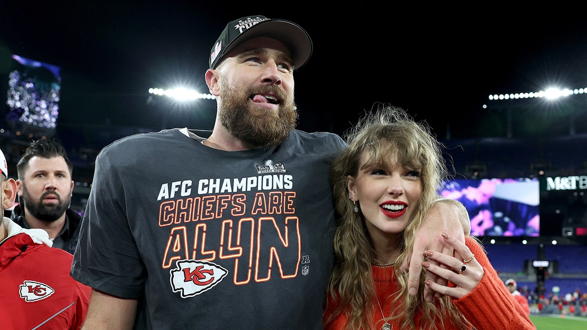 Travis Kelce stands with his arm around Taylor Swift