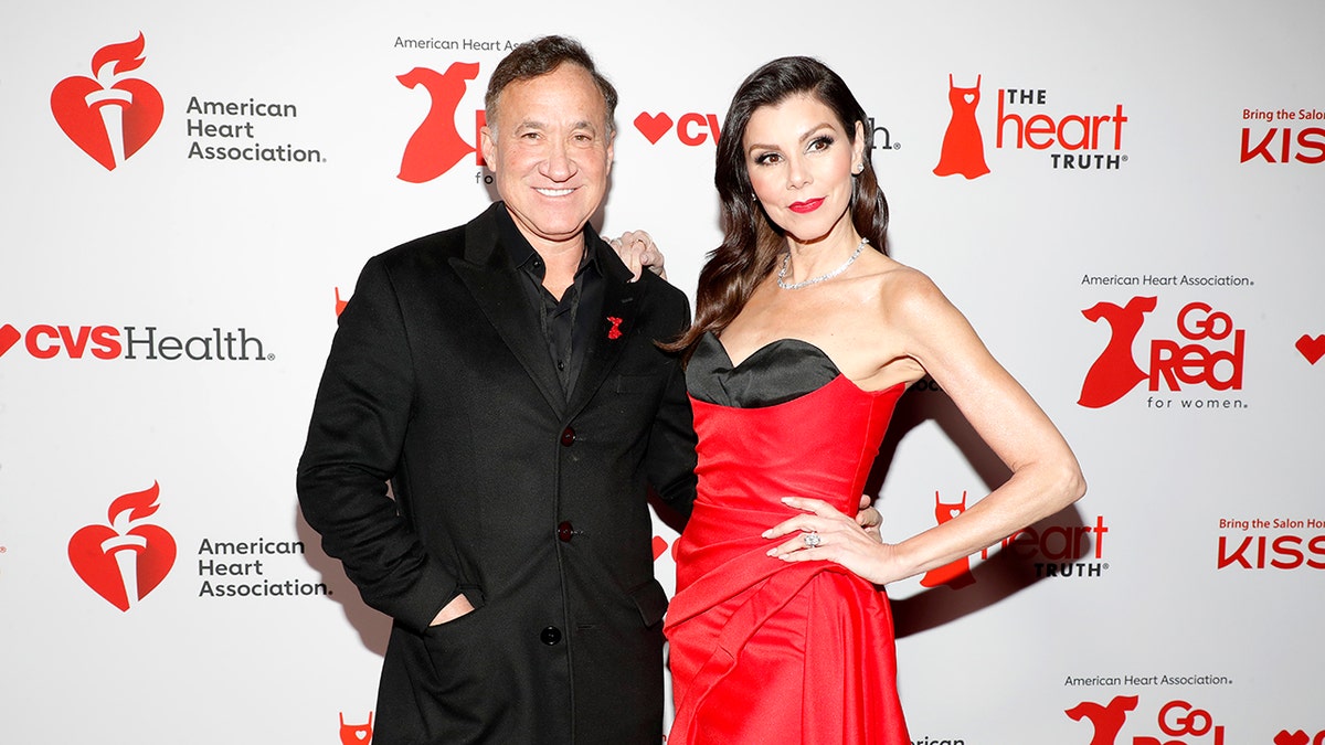 Dr. Terry Dubrow posing next to Heather Dubrow in a red dress