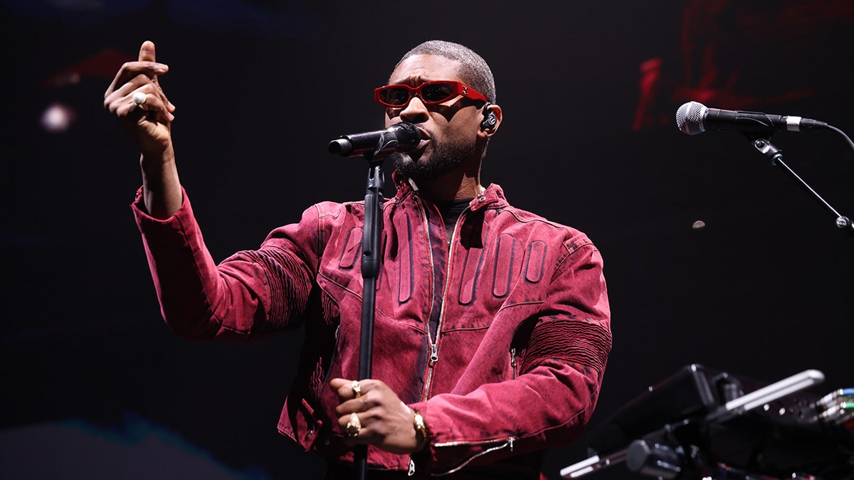 Usher se apresentando no palco com óculos escuros