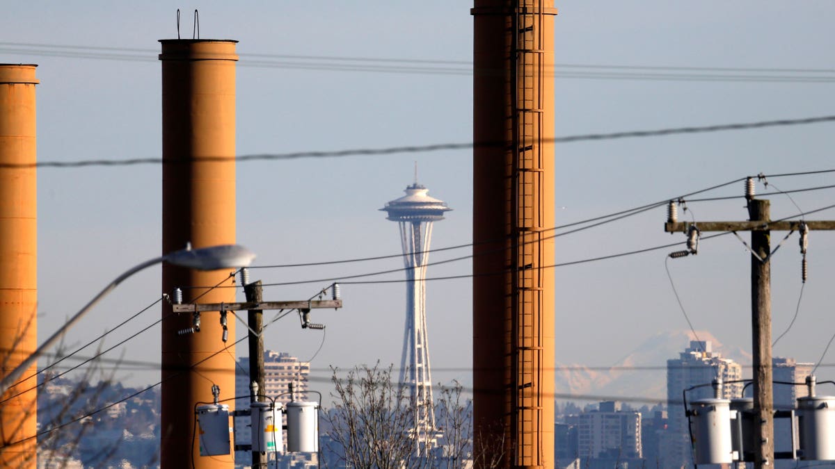 The Space Needle is seen in view of still-standing but now defunct stacks at a steel plant