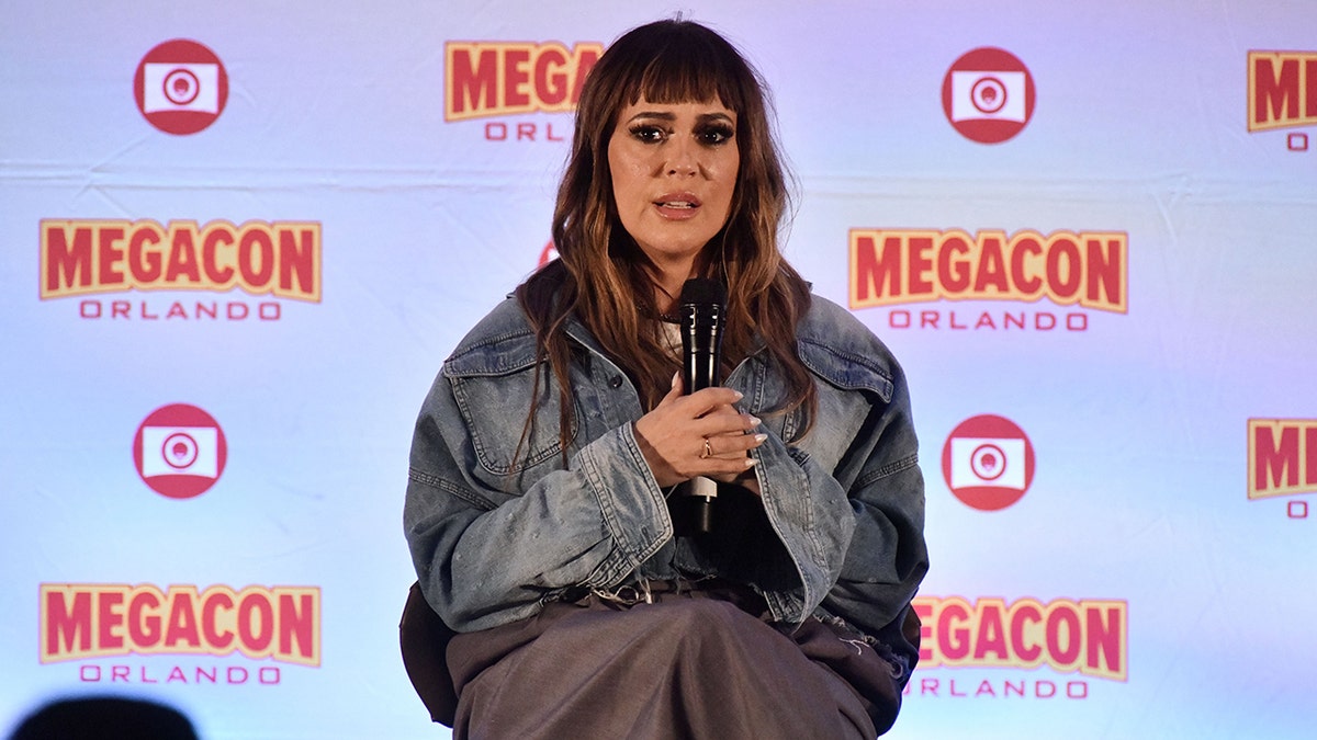Alyssa Milano in a jean jacket looks serious on stage at MegaCon Orlando
