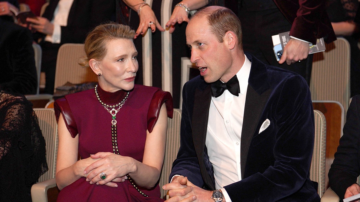 Prince William seated next to Cate Blanchett in a red cap sleeve dress at the BAFTAS