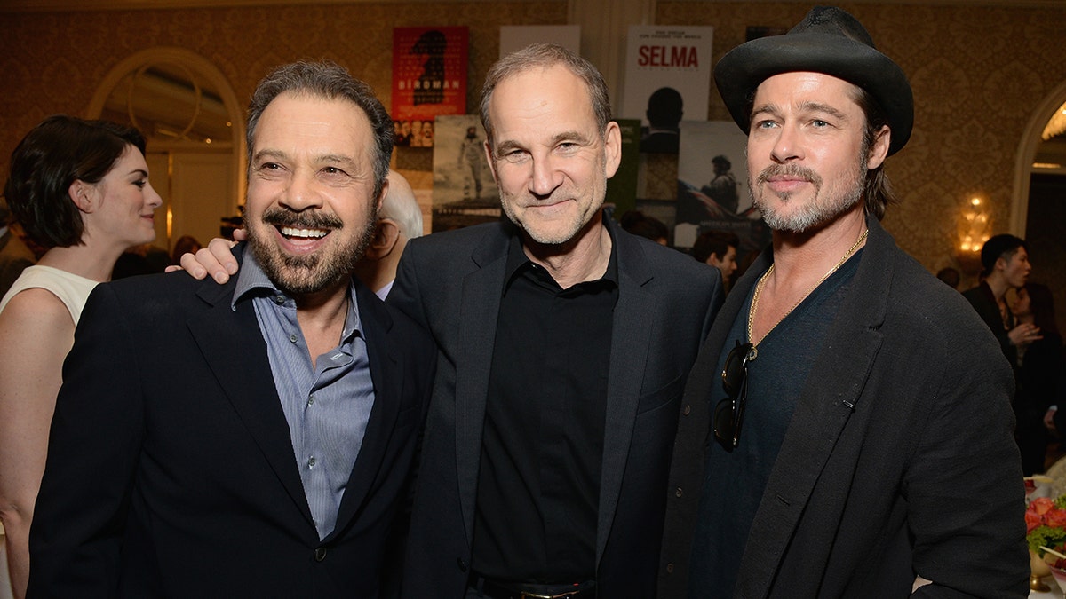 O diretor Edward Zwick e seu parceiro de produção Marshall Herskovitz sorriem no almoço do AFI Awards com Brad Pitt usando um chapéu preto