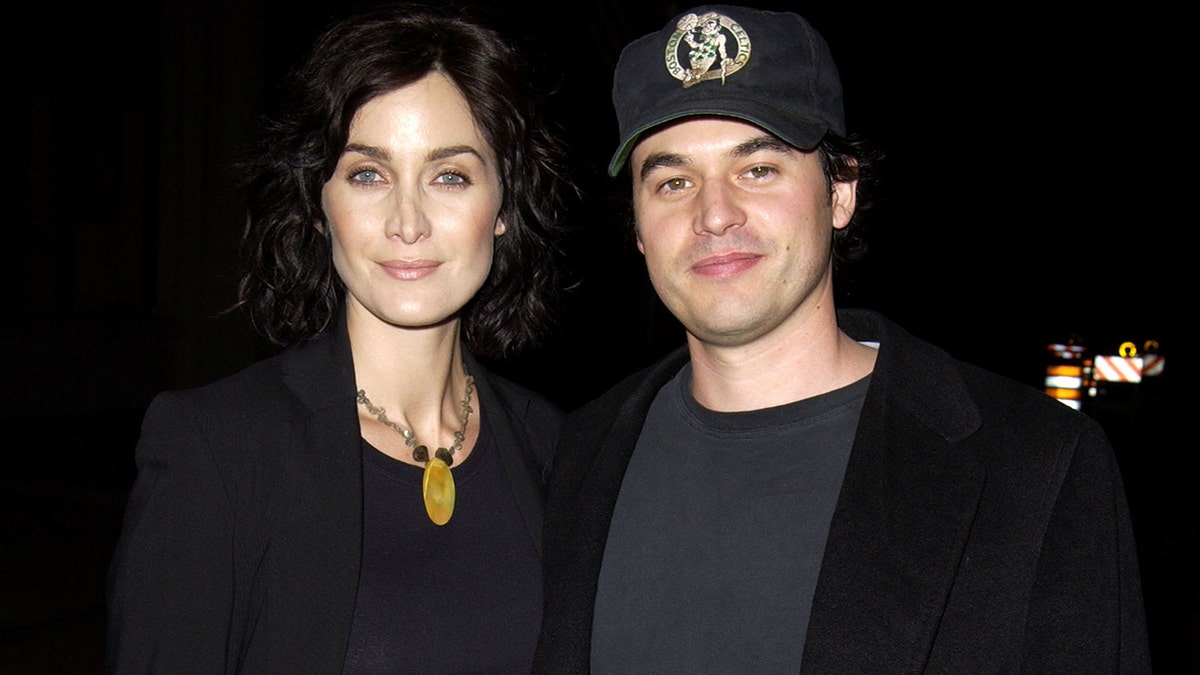 Carrie-Anne Moss and her husband posing for a photo