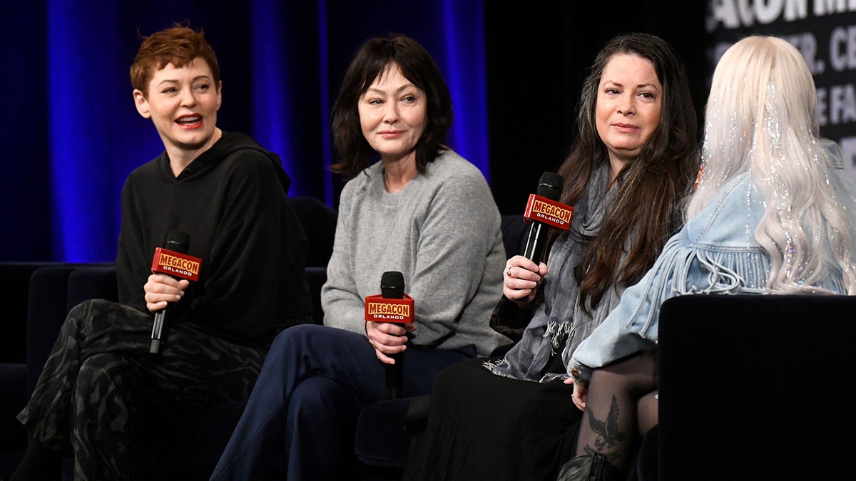 Rose McGowan smiles and sits next to Shannen Doherty and Holly Marie Combs on stage at MegaCon Orlando