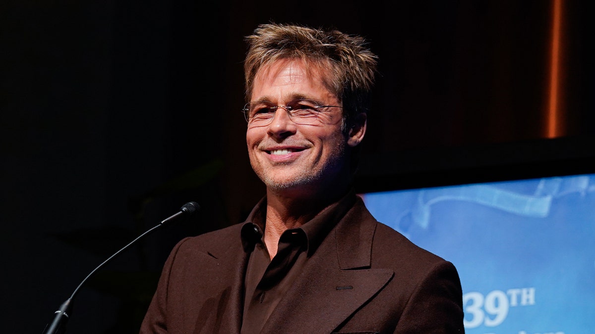 Brad Pitt smiles wearing a brown suit at SBIFF