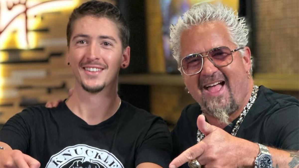 Hunter Fieri in a black shirt with a graphic smiles next to father Guy Fieri with sunglasses on