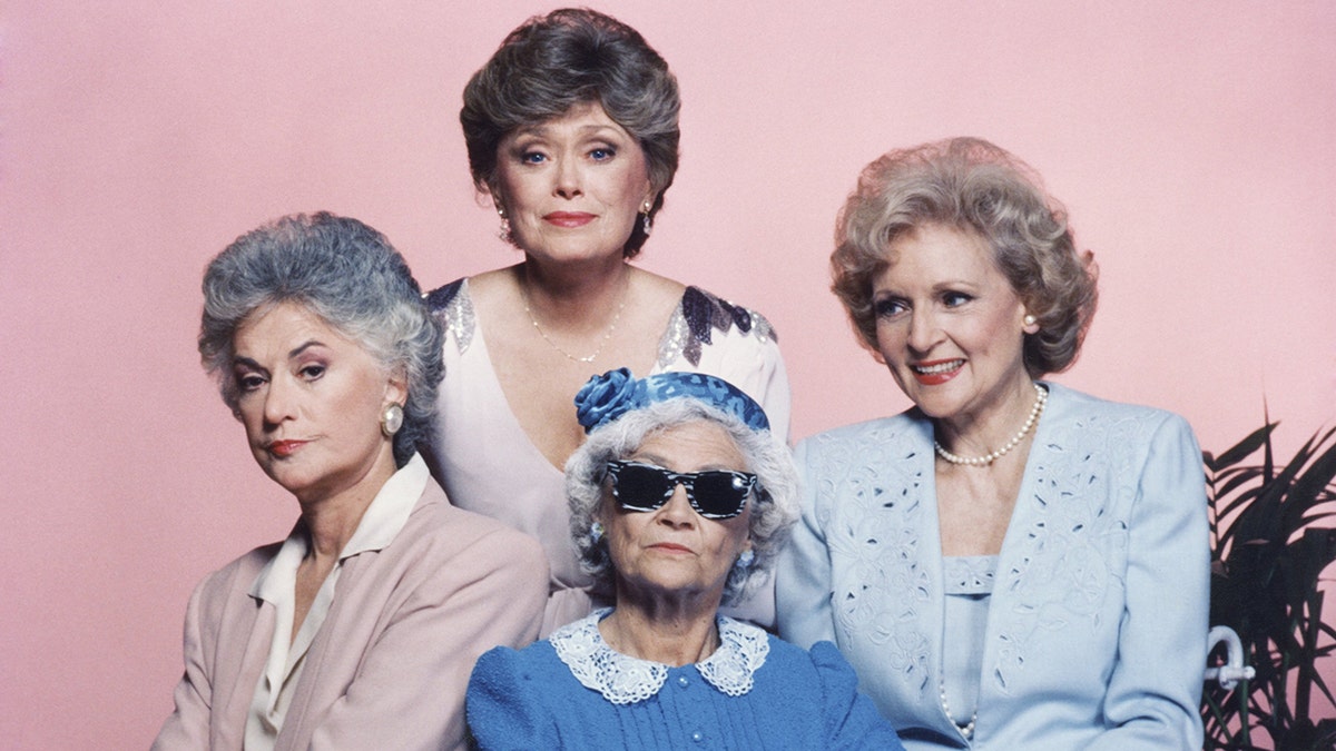 Bea Arthur looks serious as Dorothy, in front of Rue McClanahan in the back with Betty white smiling looking to her left and Estelle Getty in the front for a promotional picture of "Golden Girls"