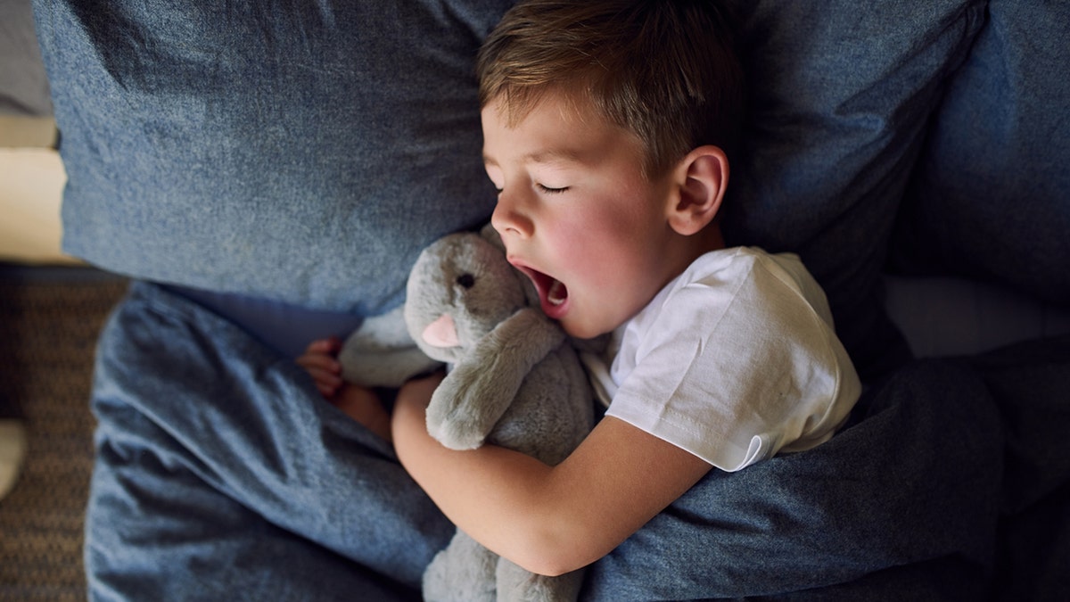 little boy yawns in bed