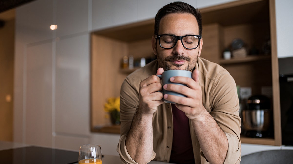 man drinking coffee in a kitchen