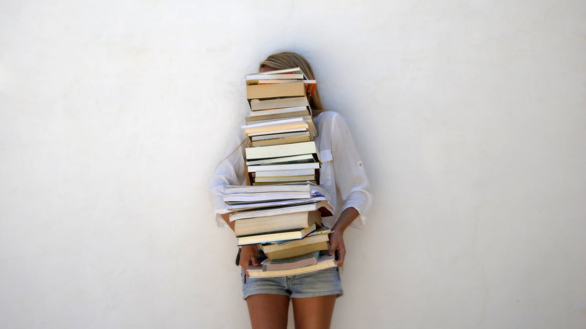 Woman hidden behind a stack of books