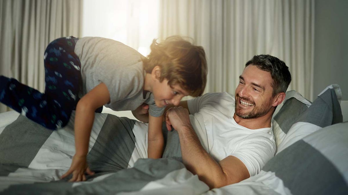 boy jumping on father's bed