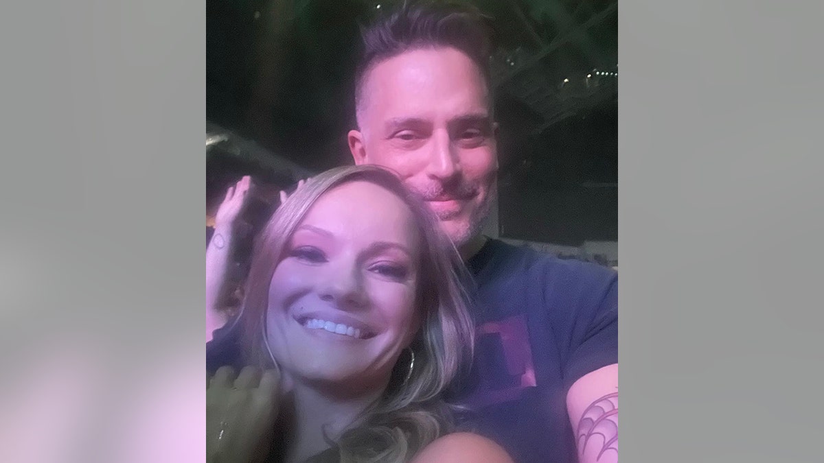 Joe Manganiello soft smiles behind his girlfriend Caitlin O'Connor grinning