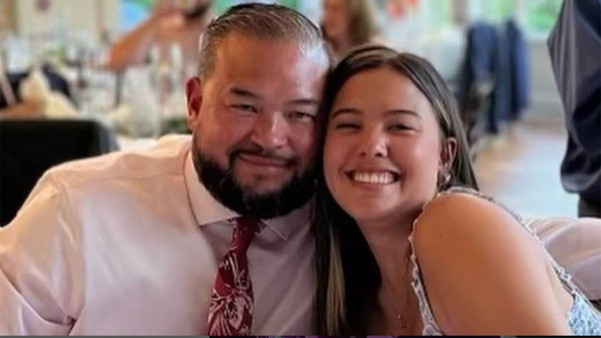 John Gosselin in a light pink shirt and patterned tie smiles next to Hannah Gosselin at a table