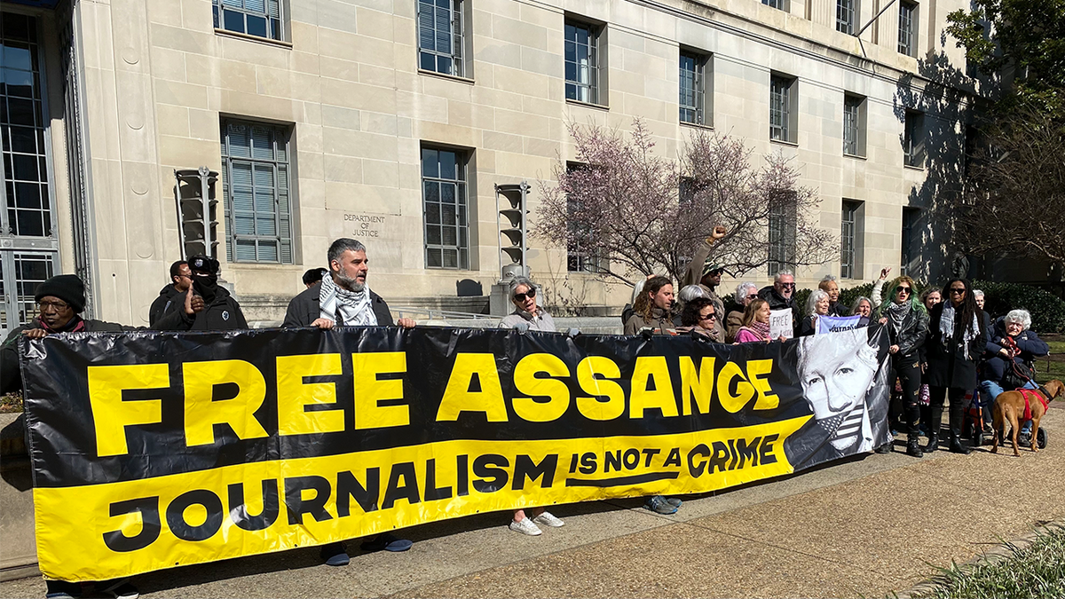 Julian Assange supporters hold a sign at a rally outside the Justice Department