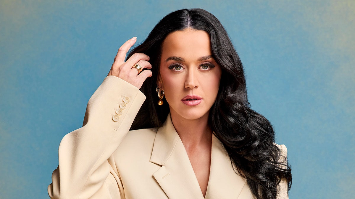 Katy Perry lifts her fingers to her hair in a cream jacket for "American Idol" shoot