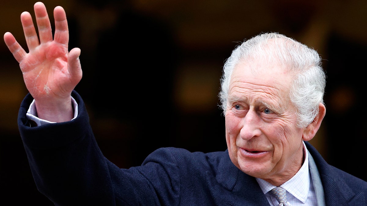 O rei Charles em um terno azul-marinho acena para os espectadores ao sair da Clínica de Londres