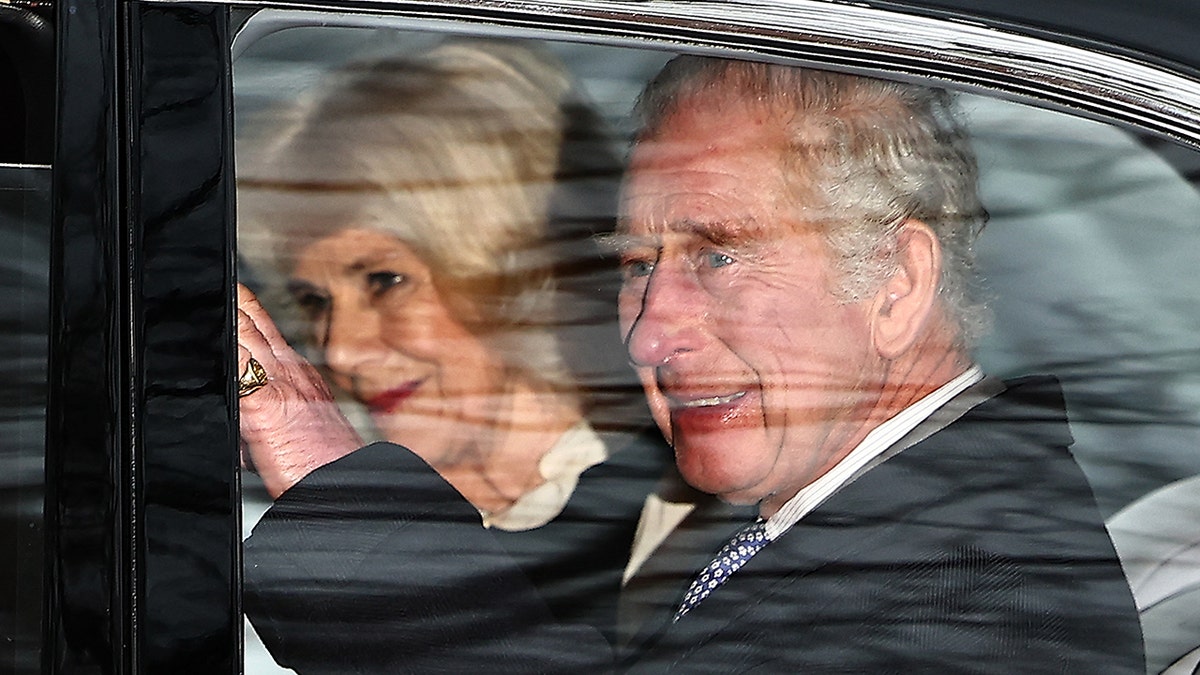 King Charles waves out his car window seated next to Queen Camilla as he leaves Clarence House