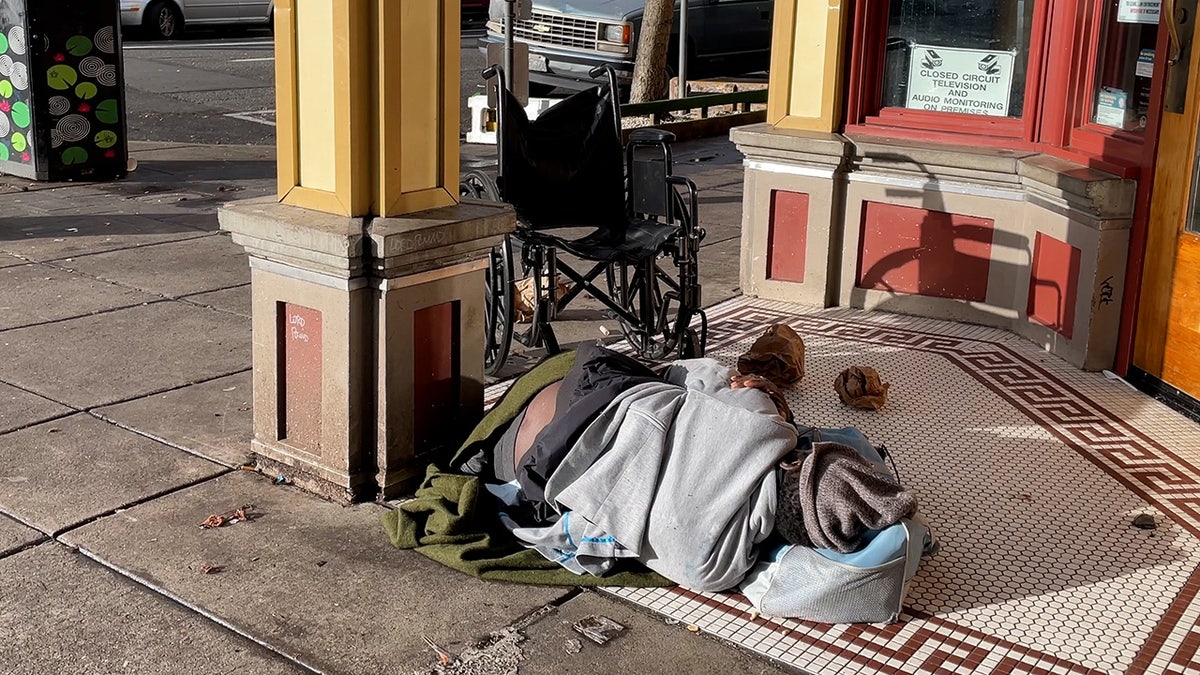 Man sleeps on ground in front of business in Portland
