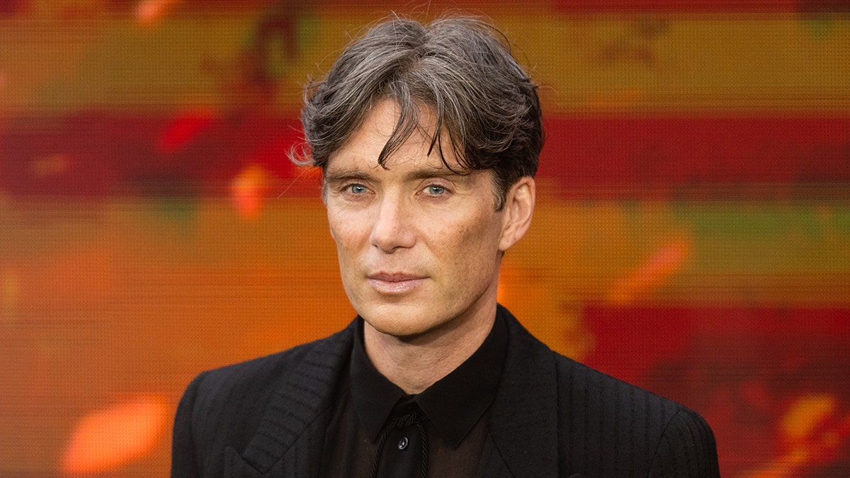 Cillian Murphy smirks subtly on the carpet in all black for Oppenheimer