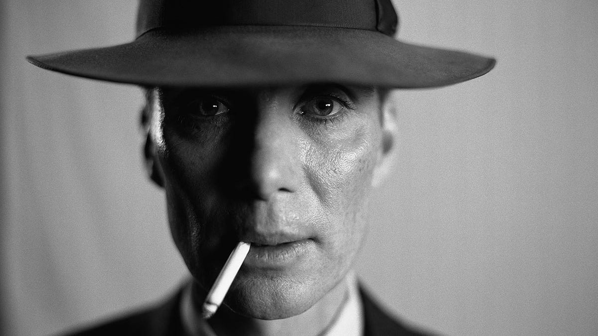 Black and white photo of Cillian Murphy as J. Robert Oppenheimer looking directly into the camera with a cigarette in his mouth